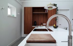 Keukeneiland uit LG Hi-Macs solid surface, met notenhouten wandmeubel.